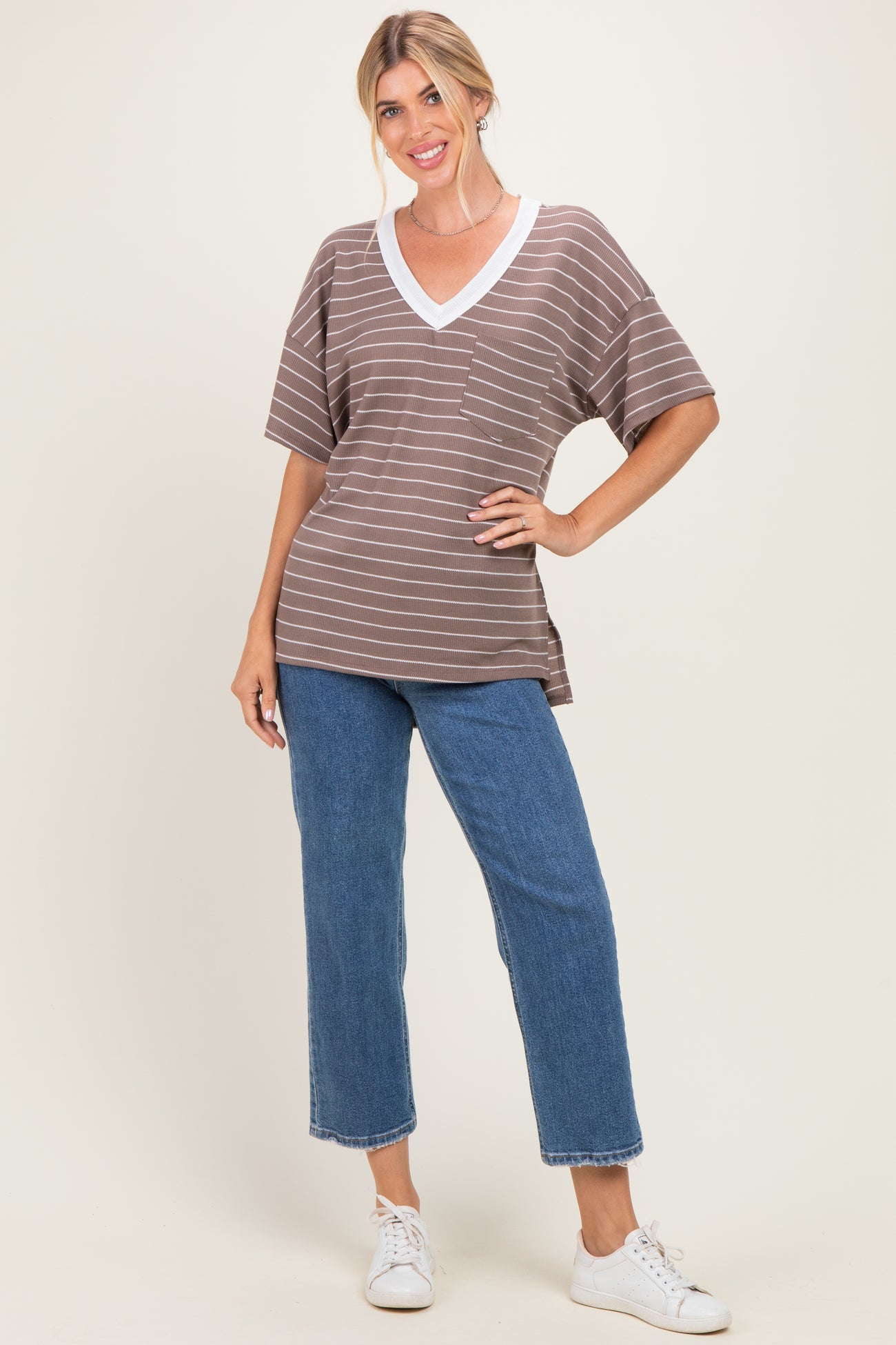 woman wearing a brown and white striped short sleeve top with a pocket and light wash wide-leg jeans