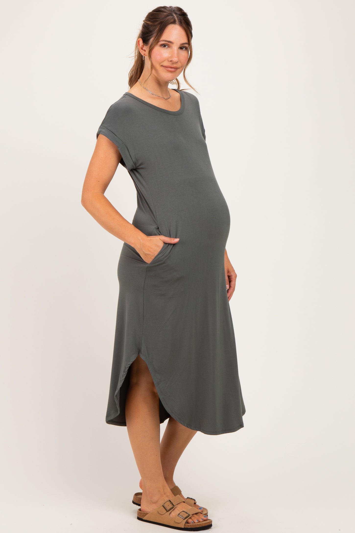 woman wearing a dark gray short sleeve maternity dress with pockets and a baby bump visible