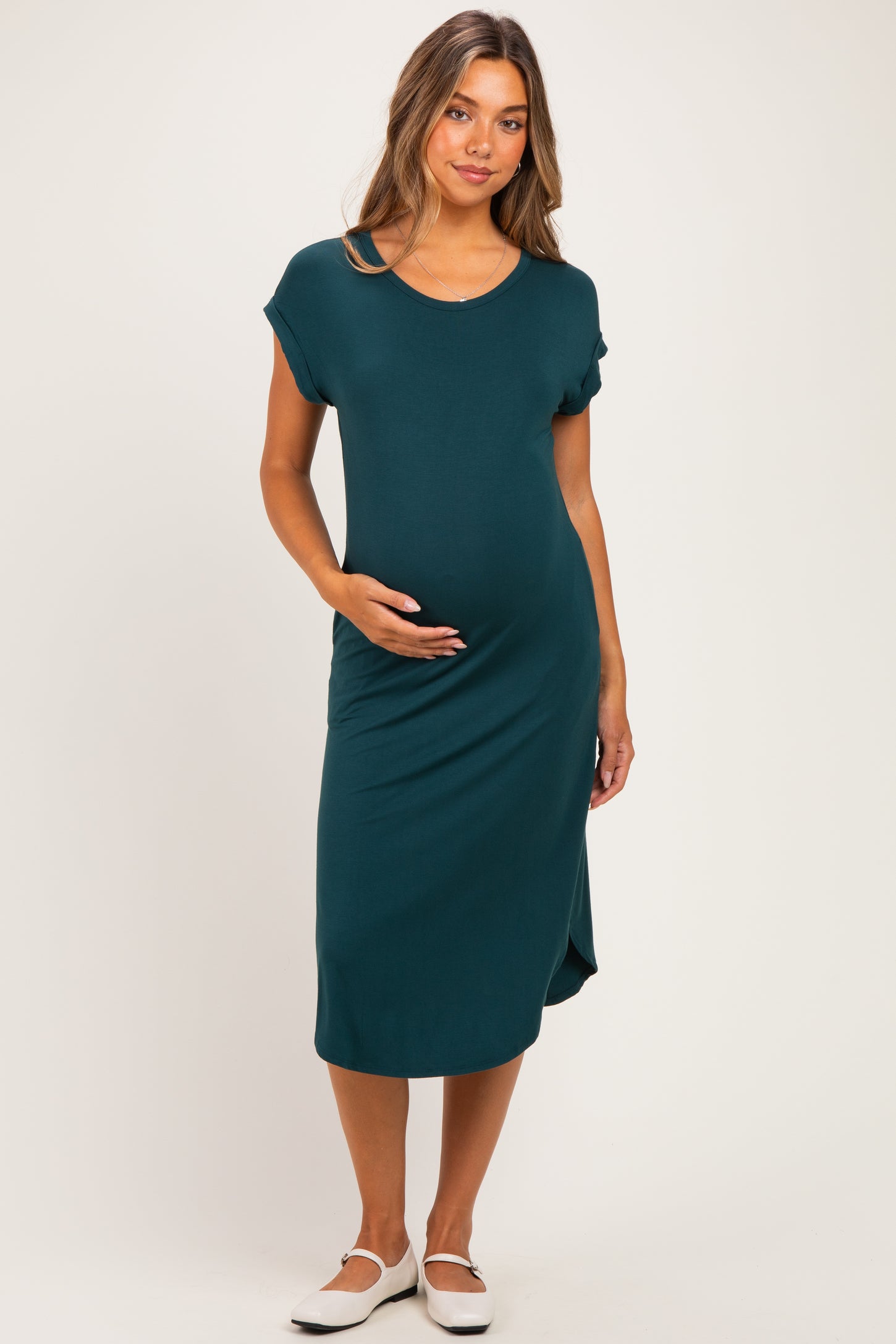 woman wearing a teal maternity midi dress and holding her baby bump
