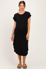 woman wearing a black short sleeve maternity dress with a scoop neckline and side slits, showing a baby bump
