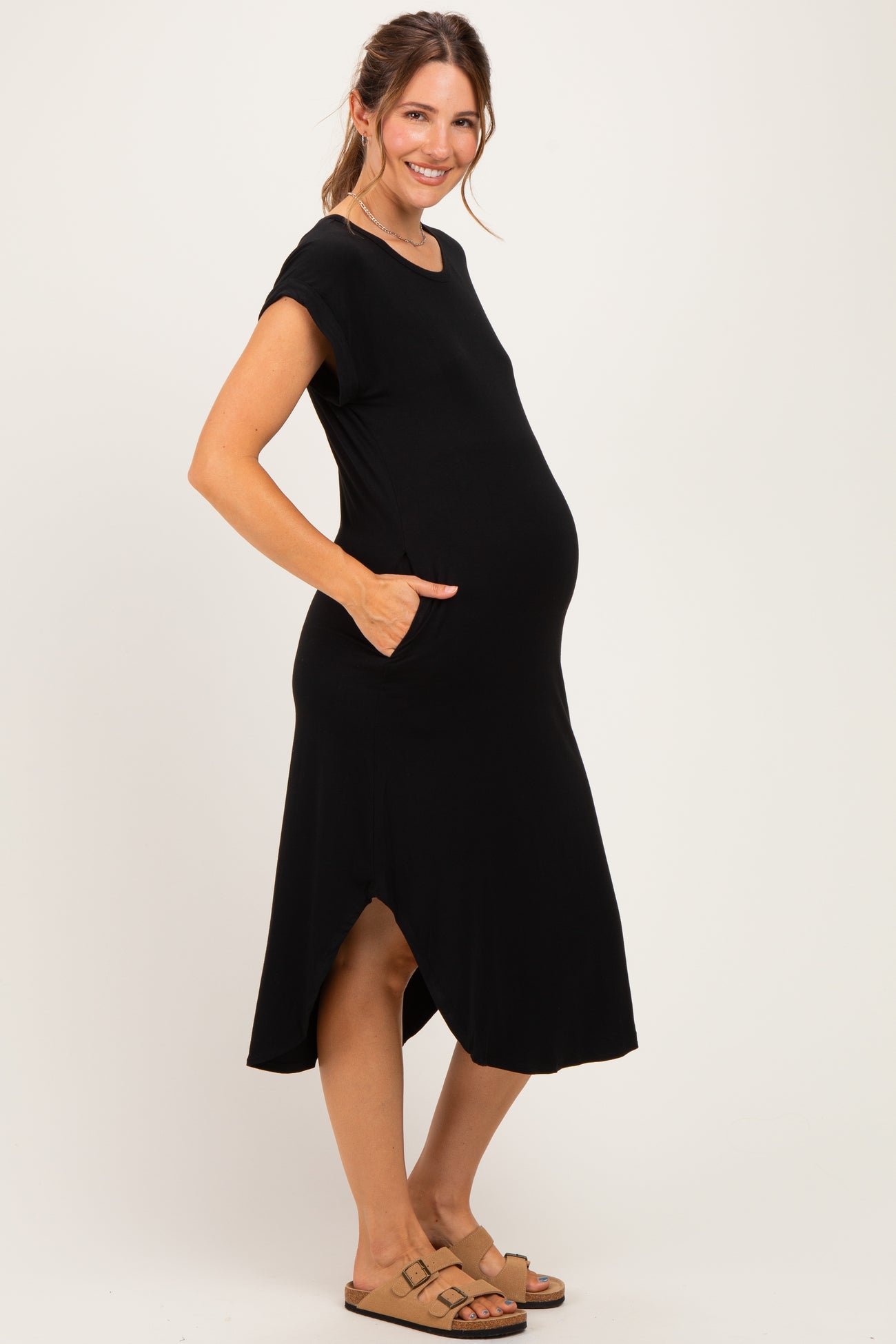 woman wearing a black short sleeve maternity dress with pockets and a visible baby bump