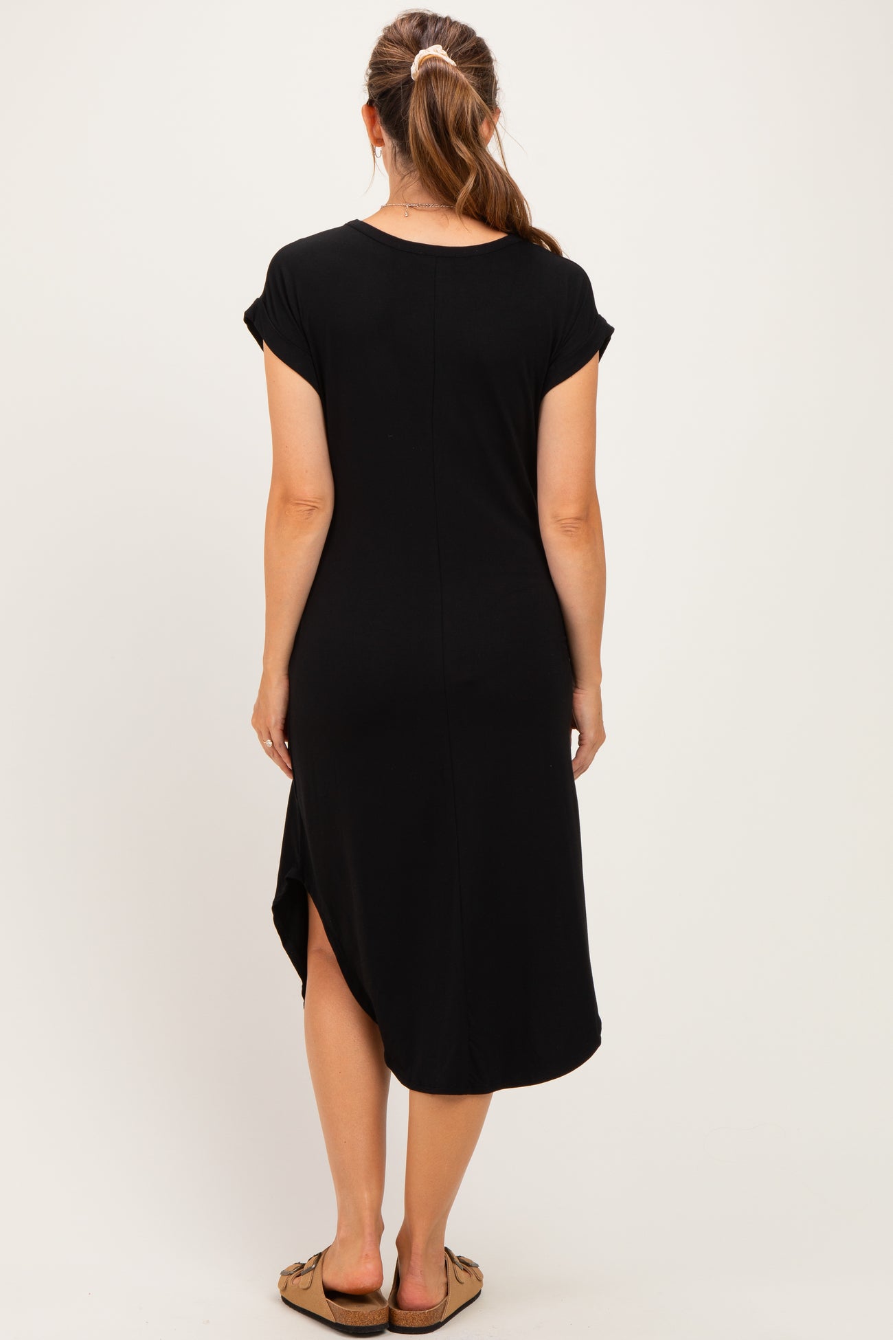 woman wearing a black maternity dress with short sleeves and a side slit, showing a baby bump from the back