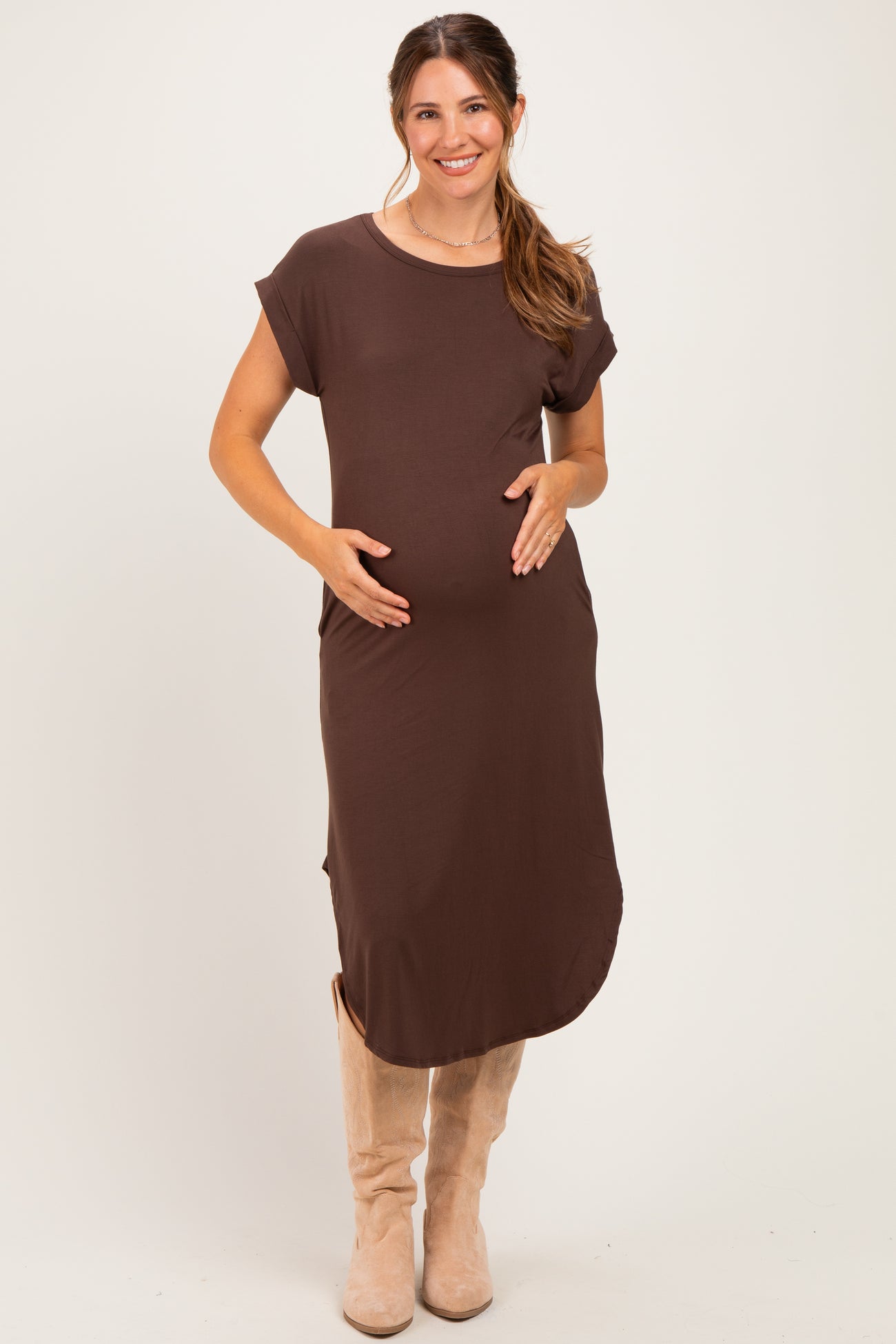 woman wearing a brown short sleeve maternity dress and holding her baby bump