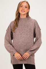 woman wearing a mauve maternity sweater with a high neck and balloon sleeves, showcasing her baby bump