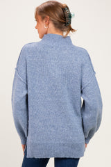 woman wearing a light blue oversized maternity sweater with a high neck and dropped shoulders