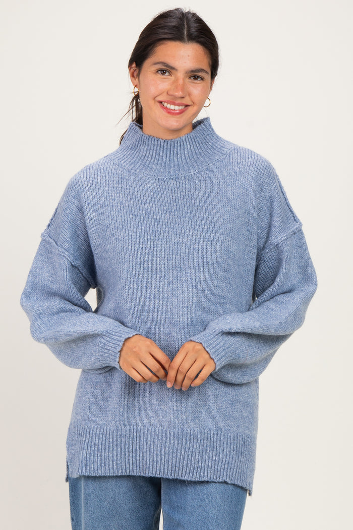 woman wearing a light blue oversized knit sweater with a high neckline and loose sleeves
