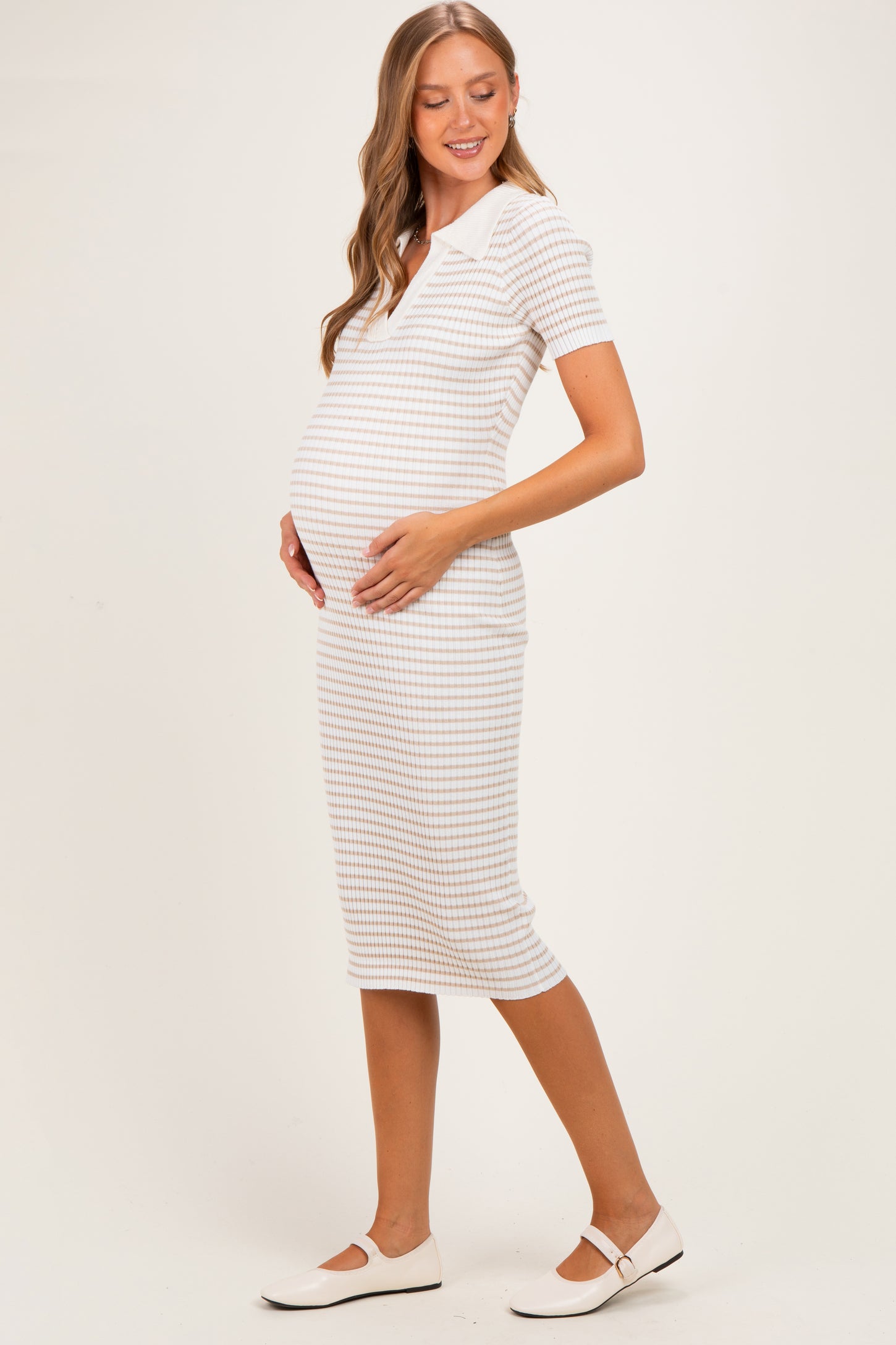 woman wearing a striped maternity dress with short sleeves and a collar, cradling her baby bump