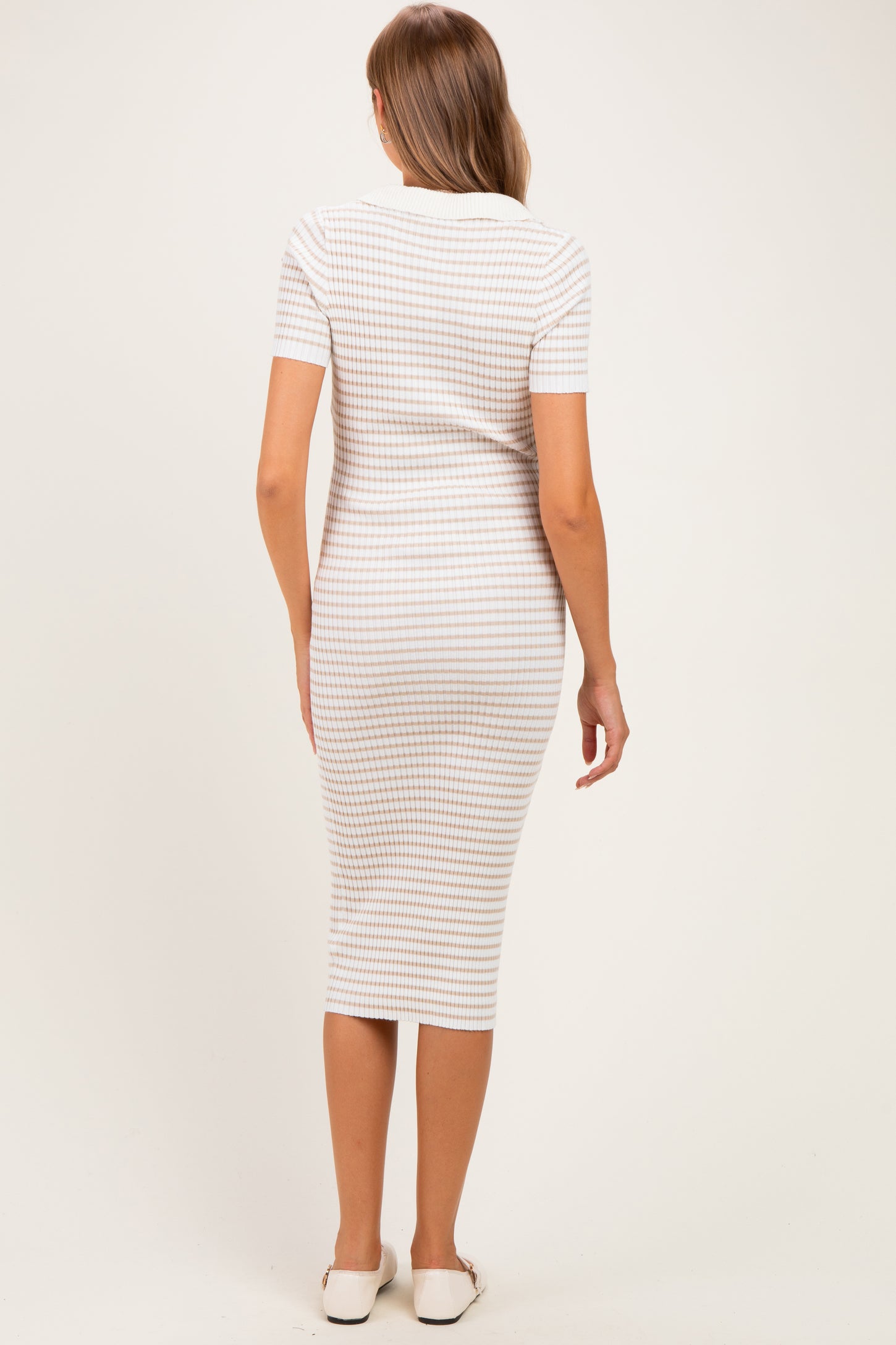woman wearing a fitted white and beige striped maternity dress with short sleeves, showing a baby bump from the back