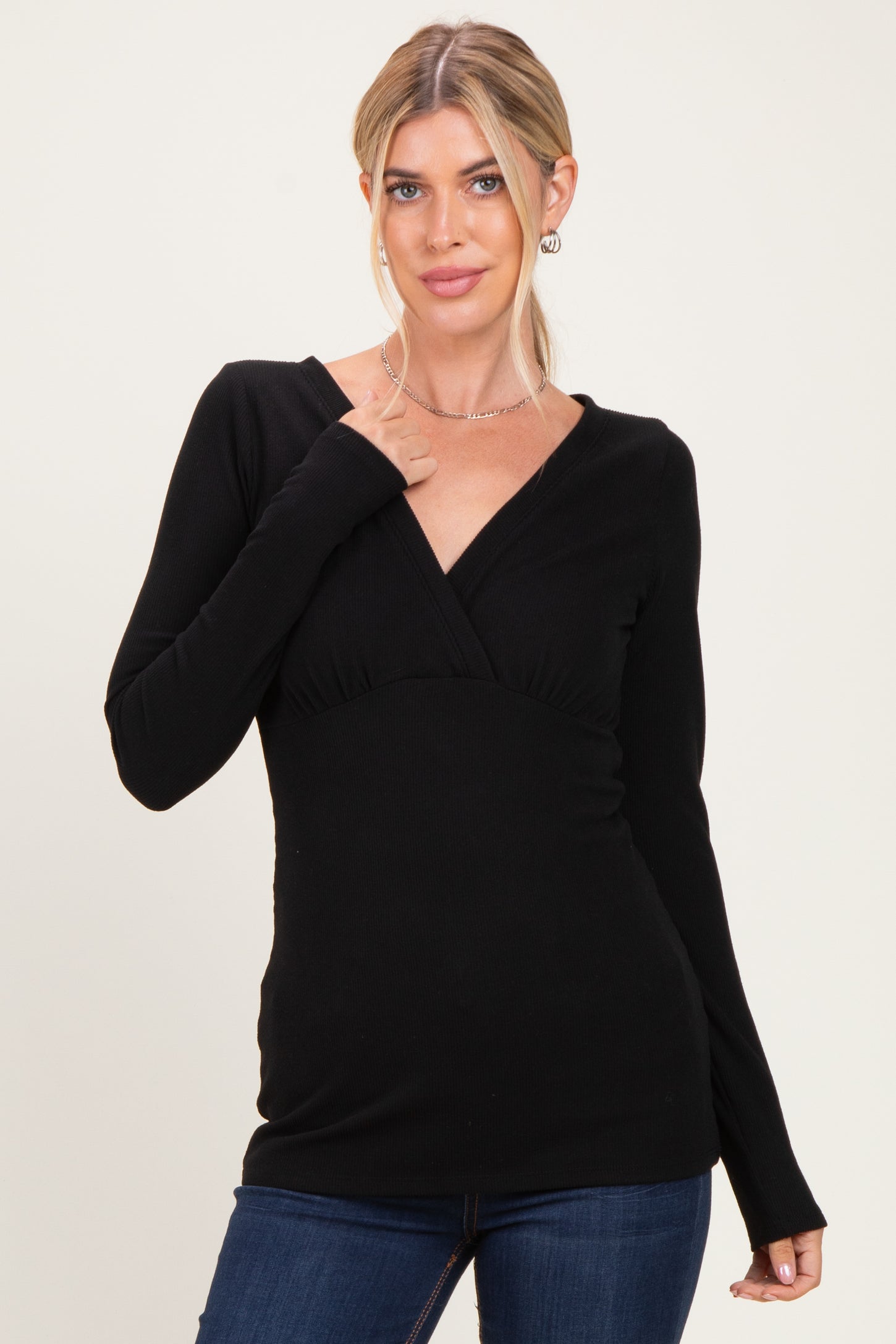 woman wearing a black long sleeve wrap top with a fitted waist and v-neckline