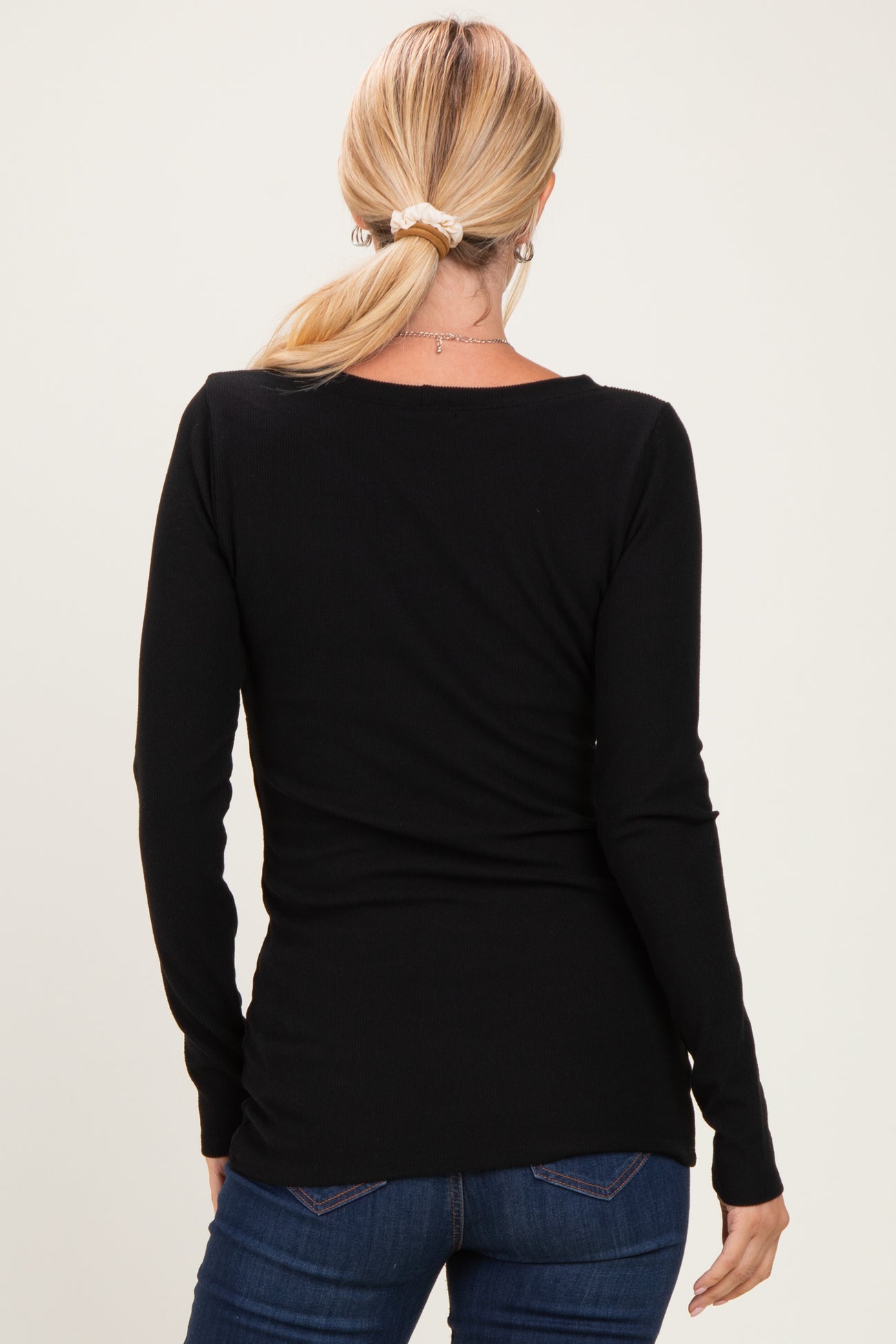 woman wearing a black long sleeve fitted top, seen from the back, paired with blue jeans