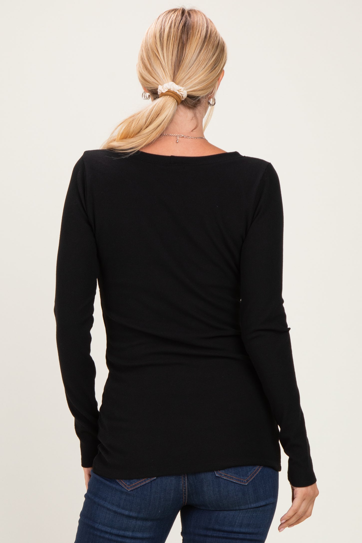 woman wearing a black long sleeve fitted top, seen from the back, paired with blue jeans