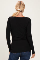 woman wearing a black long sleeve fitted top, seen from the back, paired with blue jeans