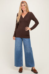 woman wearing a brown long sleeve wrap top with a fitted waist and high-waisted wide-leg jeans