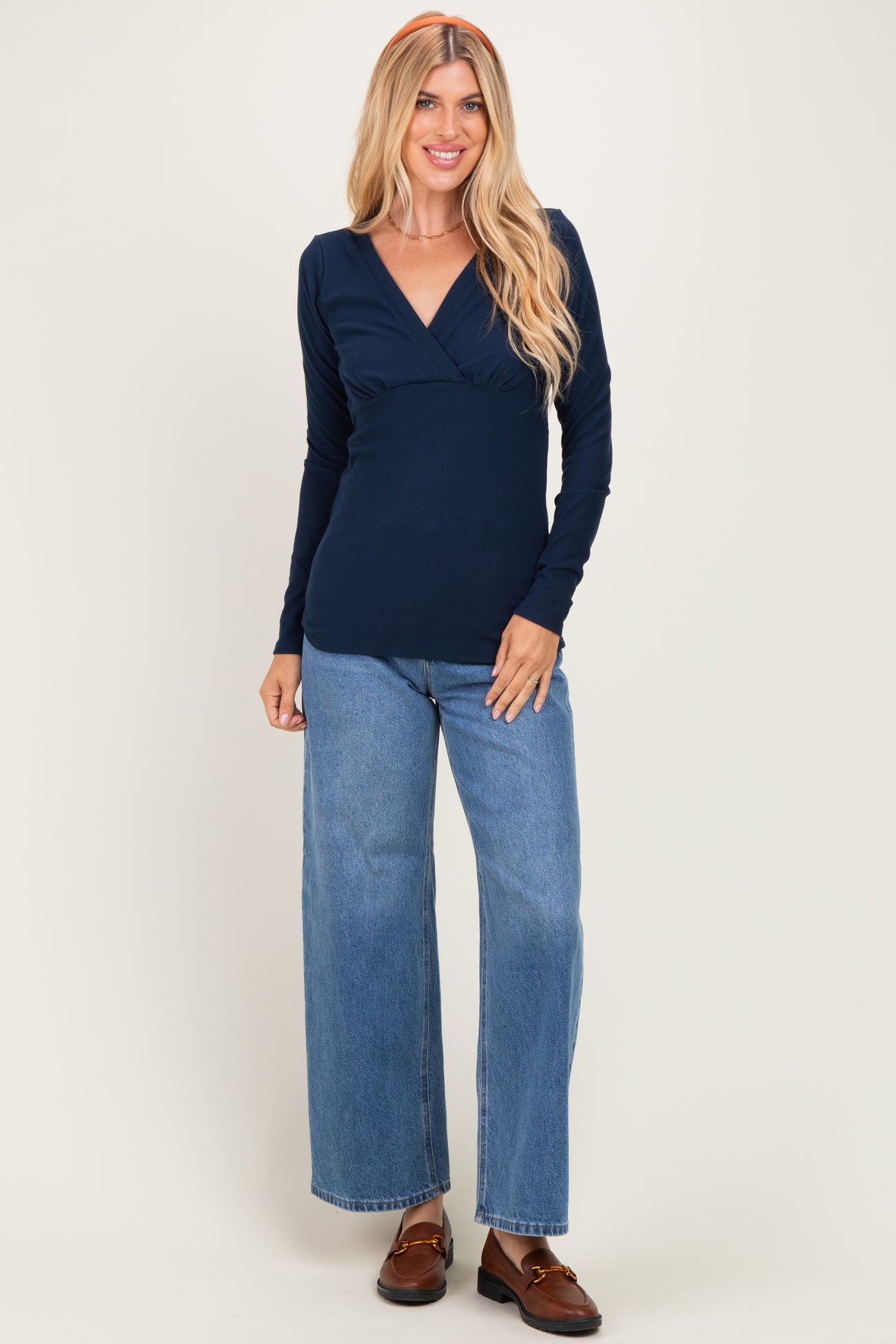 woman wearing a navy blue long sleeve wrap top and high-waisted wide-leg jeans