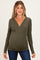 woman wearing an olive green long sleeve maternity top with a v-neck and fitted style, showing her baby bump