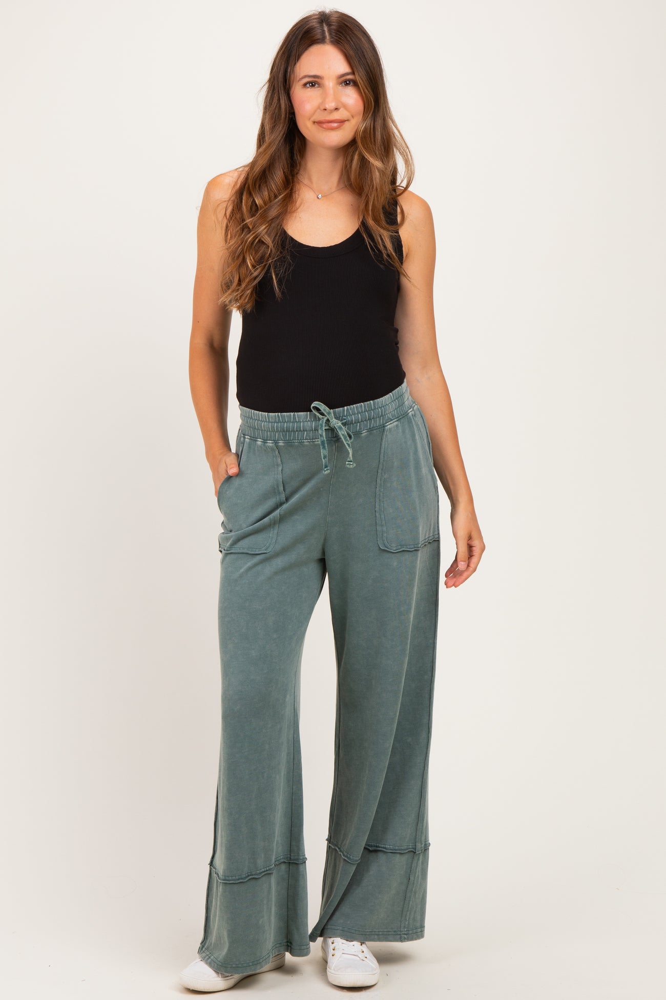 woman wearing a black tank top and green wide-leg maternity pants with pockets
