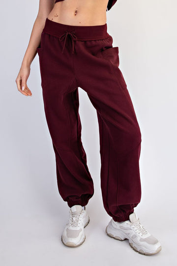 woman wearing burgundy loose-fit jogger pants with side pockets and elastic cuffs, paired with white sneakers
