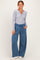 woman wearing a gray long sleeve henley top and blue wide-leg sweatpants with pockets