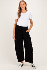 woman wearing a maternity white short sleeve top and black wide leg lounge pants, showing her baby bump