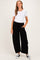 woman wearing a maternity white short sleeve top and black wide leg lounge pants, showing her baby bump
