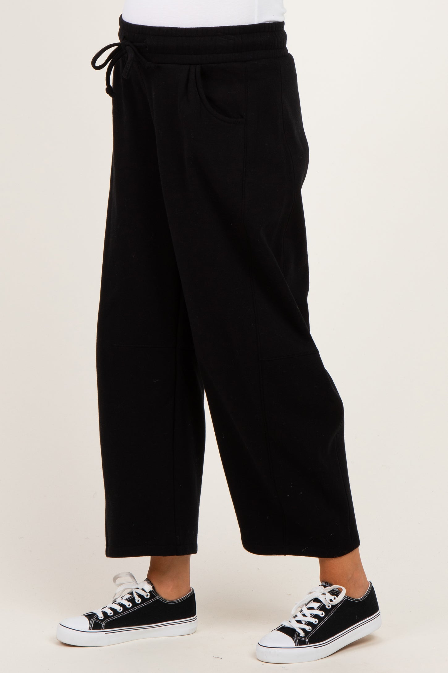 woman wearing black maternity jogger pants with an elastic waistband and side pockets, styled with black sneakers
