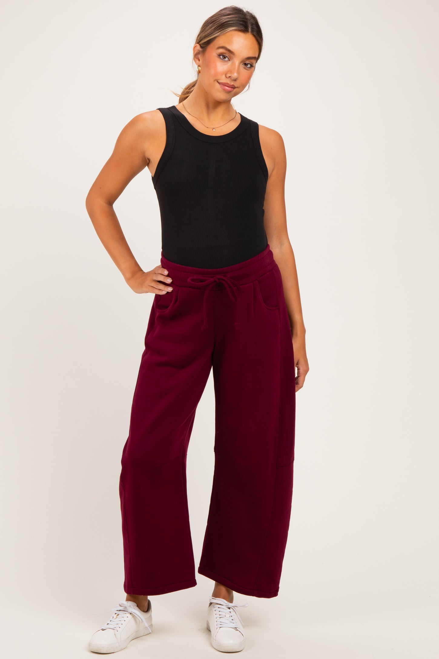 woman wearing a black ribbed tank top and burgundy wide-leg maternity pants, styled for comfort