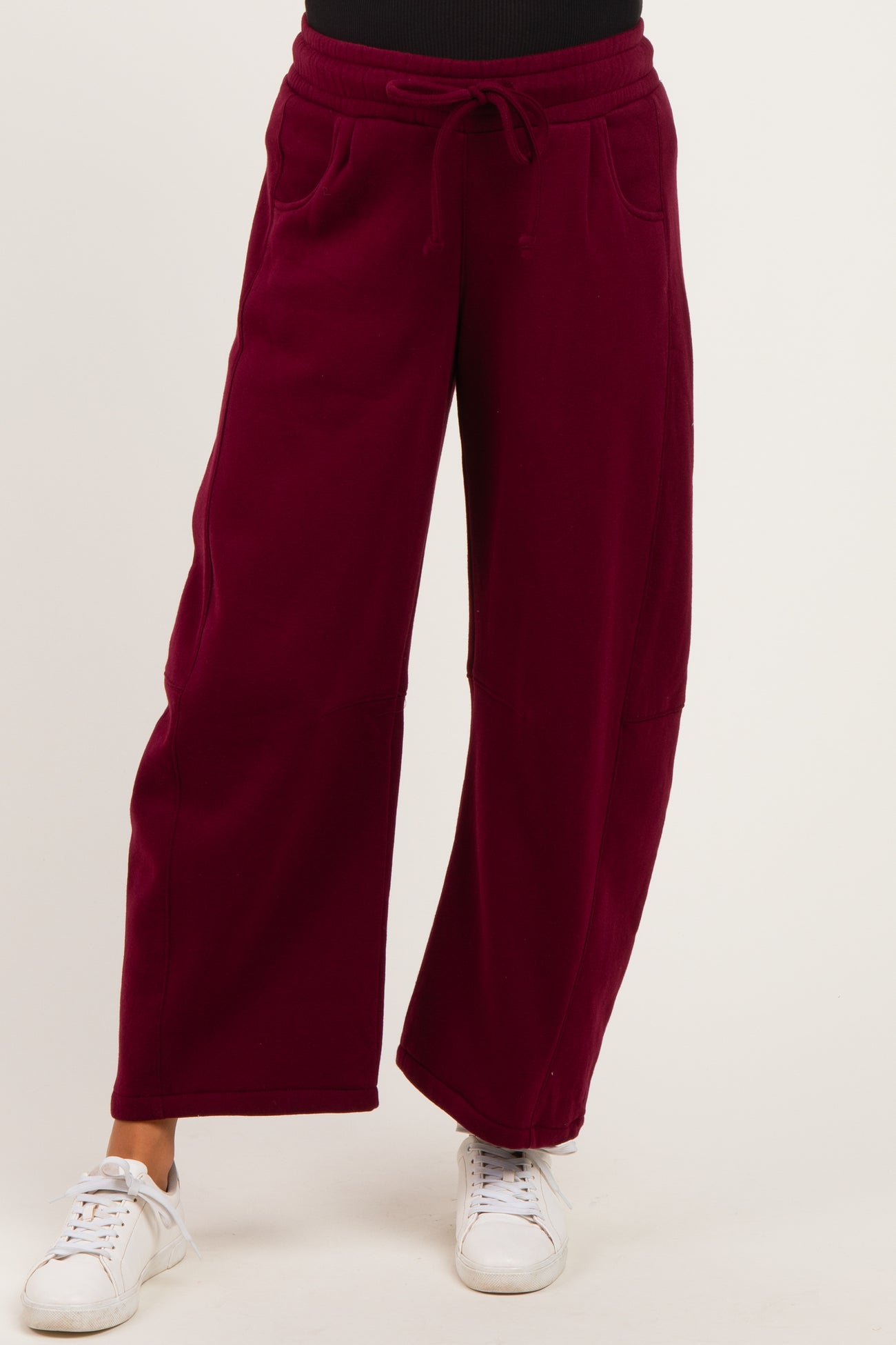 woman wearing burgundy maternity wide-leg joggers with side pockets and a drawstring waist