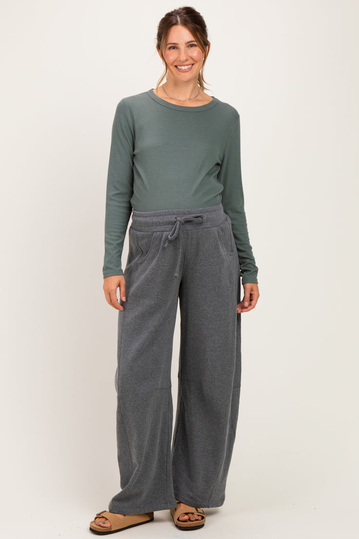 woman wearing a green long sleeve ribbed maternity top and gray wide-leg maternity sweatpants, smiling