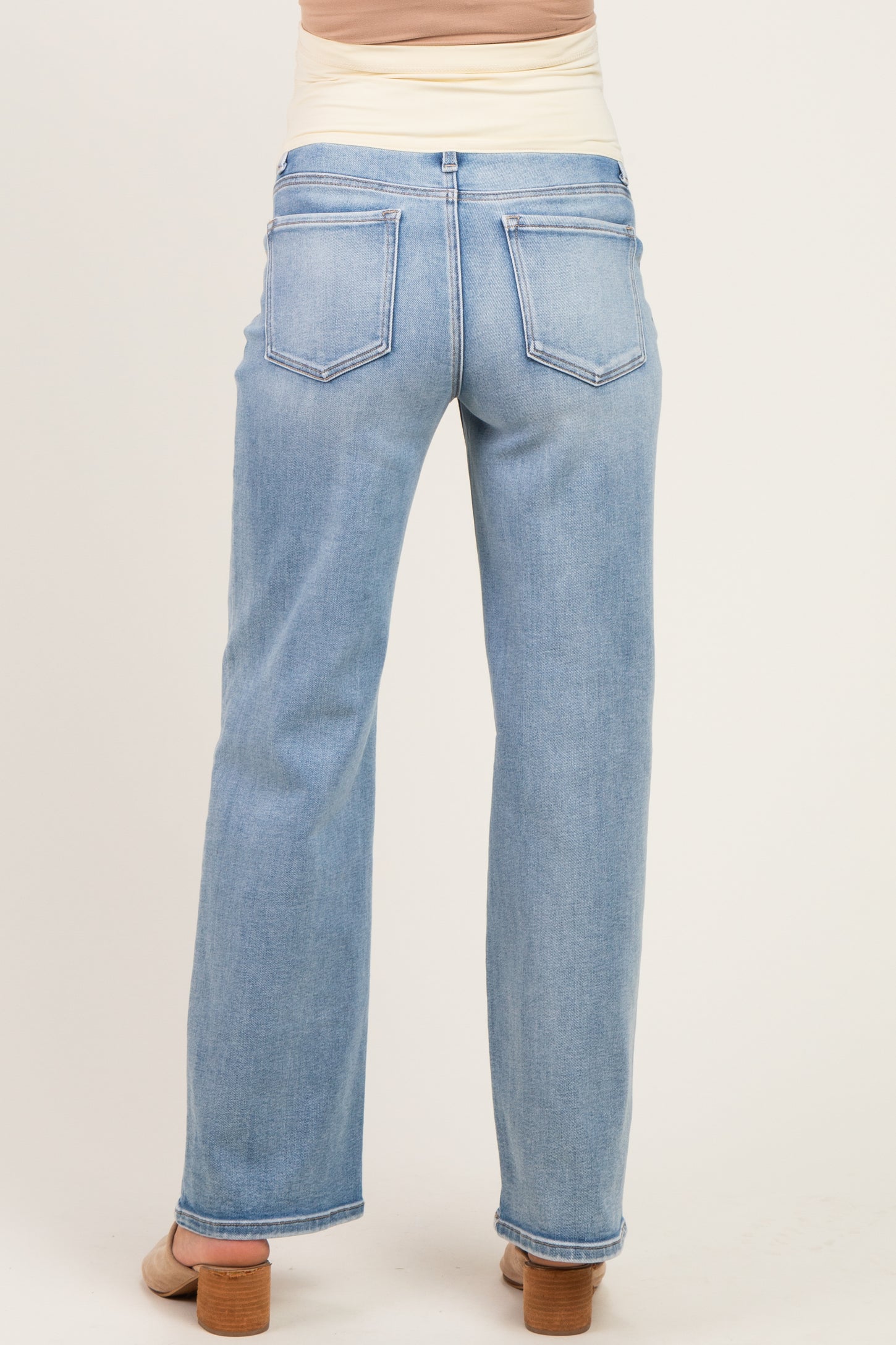 woman wearing light blue maternity jeans, viewed from the back, with a relaxed fit and subtle detailing