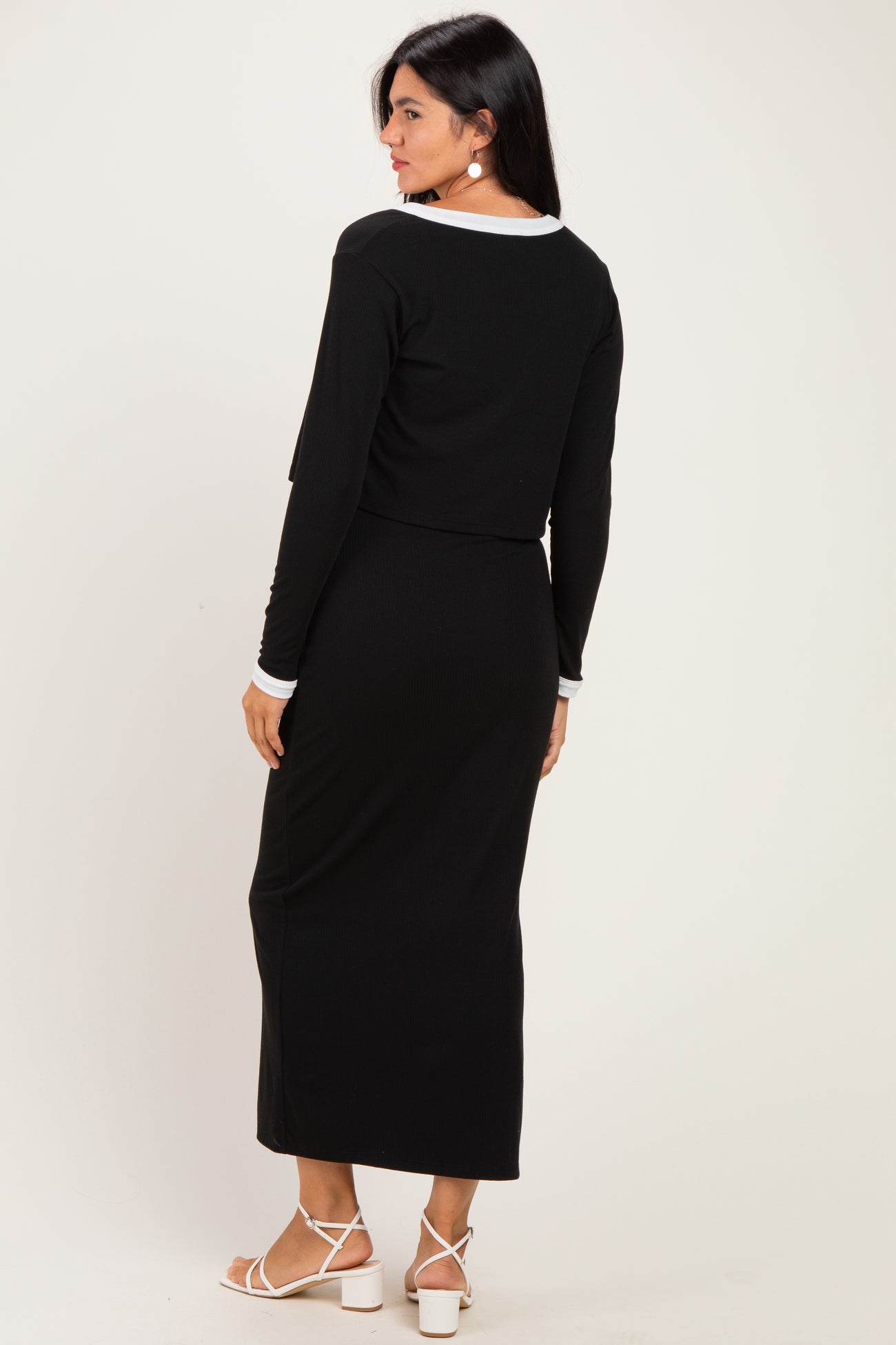 woman wearing a black long sleeve cropped top and matching maxi skirt, viewed from the back