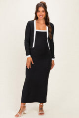 woman wearing a black maternity dress with a white trim and long sleeves, showing a baby bump