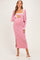 woman wearing a pink ribbed maternity dress with a side slit and a coordinating cardigan, holding her baby bump