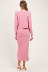 woman wearing a light pink maternity two-piece set with a cropped long sleeve top and a fitted maxi skirt