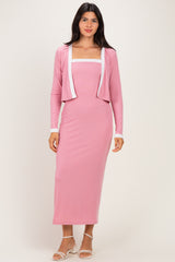 woman wearing a pink ribbed maxi dress with a matching cropped cardigan and white trim details