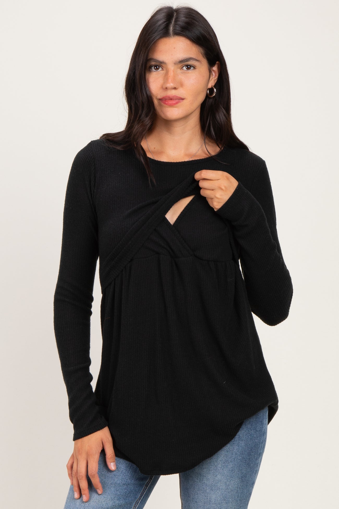 woman wearing a black long sleeve top with a twist detail and a scoop neckline, paired with blue jeans