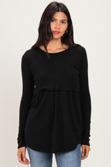 woman wearing a black long sleeve ribbed top with a layered design and a loose fit, paired with blue jeans