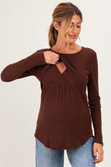 woman wearing a brown ribbed maternity top with a v-neck and lifting design to accommodate breastfeeding, showing her baby bump