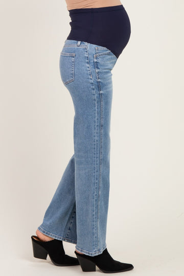 woman wearing light blue maternity jeans with a navy belly panel, showcasing a visible baby bump