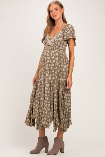 woman wearing a sage green floral maternity dress with short sleeves and a flowy skirt, showing her baby bump