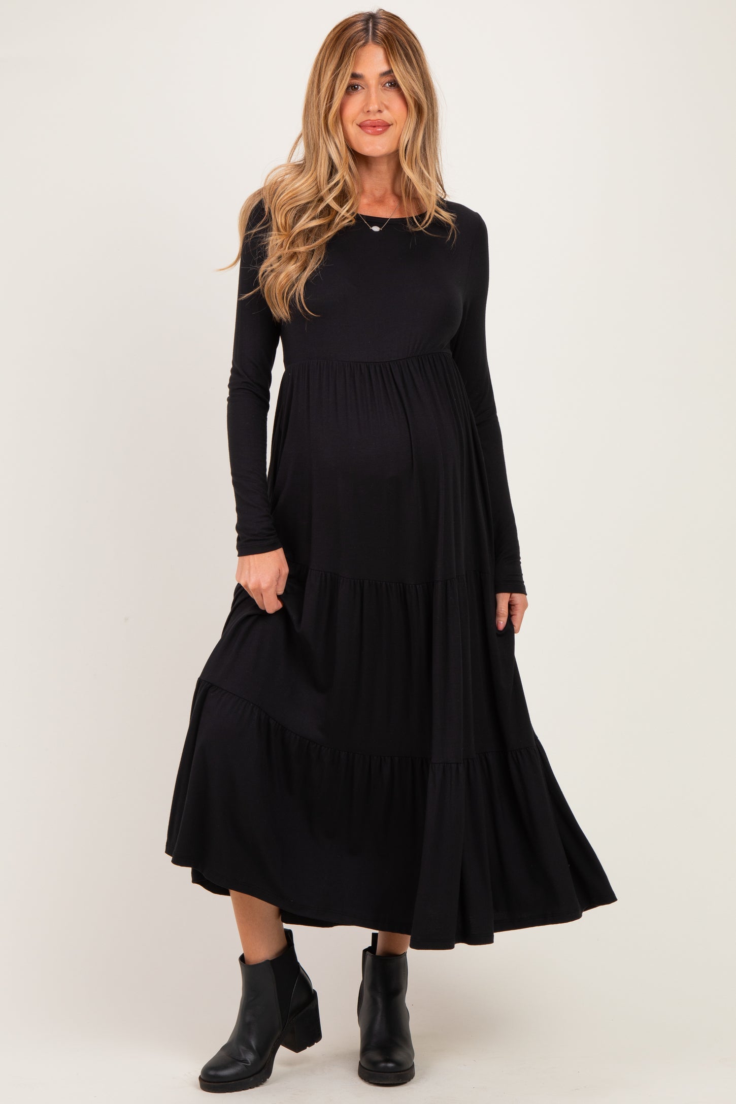 woman wearing a black long sleeve maternity dress with tiered skirt and visible baby bump