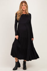 woman wearing a black long sleeve maternity dress with tiered skirt and visible baby bump