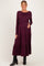 woman wearing a burgundy long sleeve maternity dress with tiered ruffles and holding her baby bump