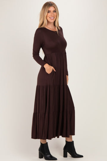 woman wearing a brown long sleeve tiered maxi dress with side pockets and black ankle boots