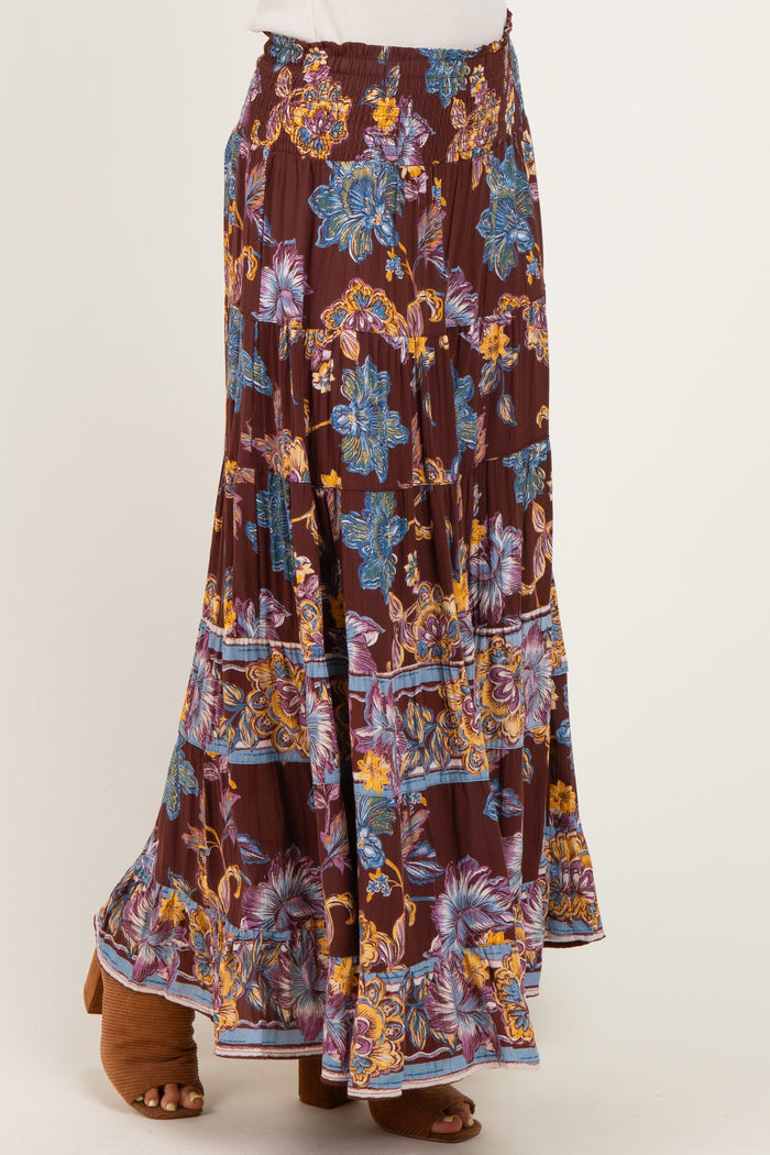 woman wearing a burgundy floral maxi skirt with a smocked waistband and layered ruffle hem