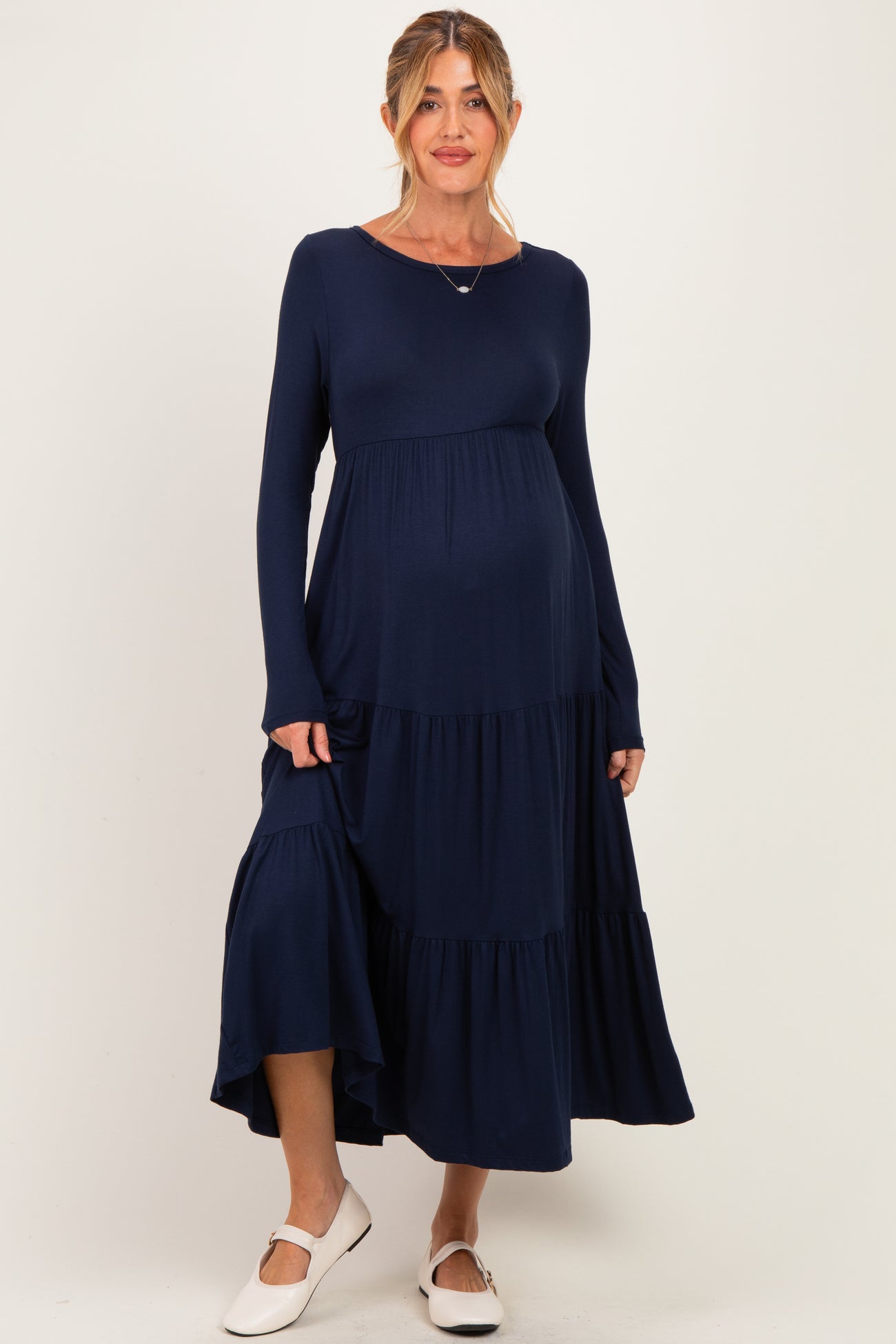 woman wearing a navy long sleeve maternity dress with tiered ruffles and a visible baby bump