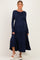 woman wearing a navy long sleeve maternity dress with tiered ruffles and a visible baby bump