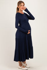 woman wearing a navy blue long sleeve maternity dress with tiered ruffles and showing her baby bump