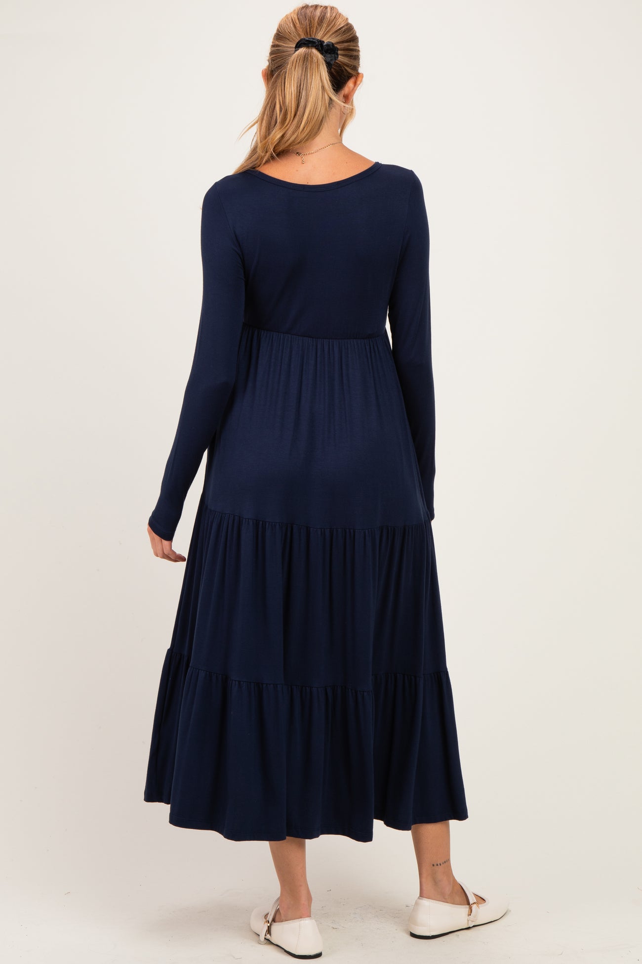 woman wearing a navy blue long sleeve maternity dress with a tiered skirt and a relaxed fit