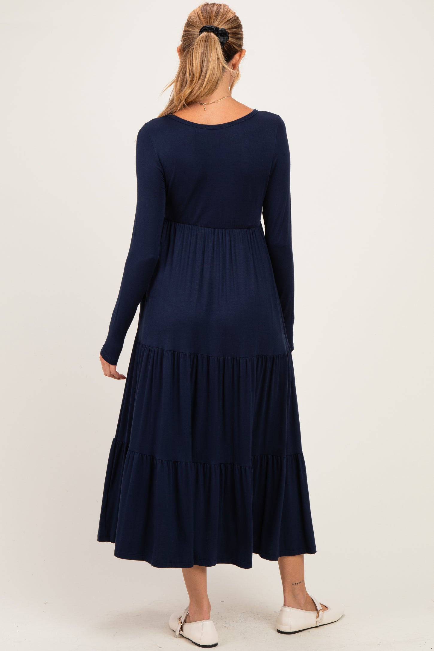 woman wearing a navy blue long sleeve maternity dress with a tiered skirt and a relaxed fit