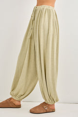 woman wearing light olive green wide-leg lounge pants with an elastic waistband and drawstring details